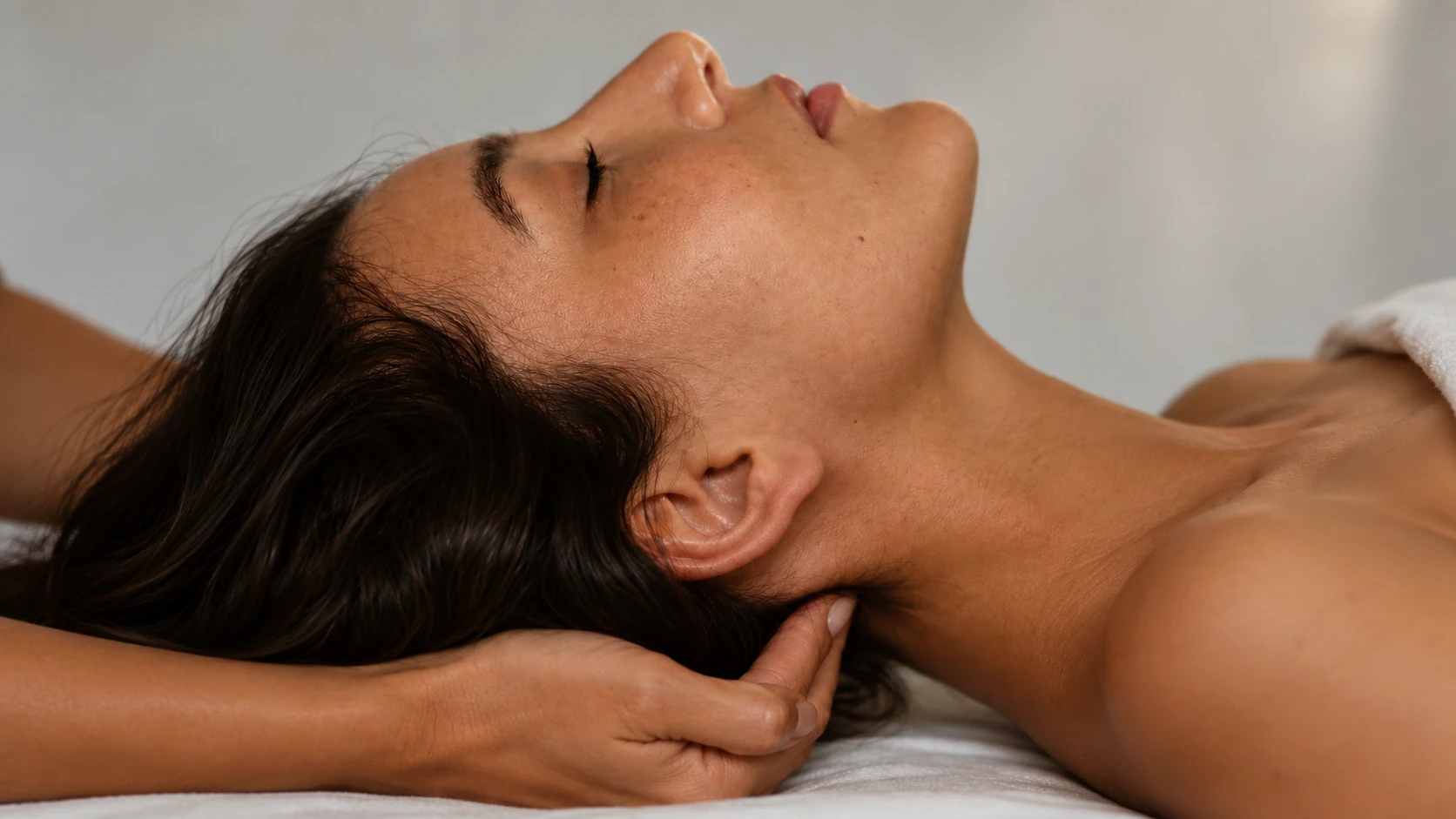Massage crânio-facial à Biarritz : une femme allongée, yeux fermés, la nuque soutenue par la main d'une praticienne